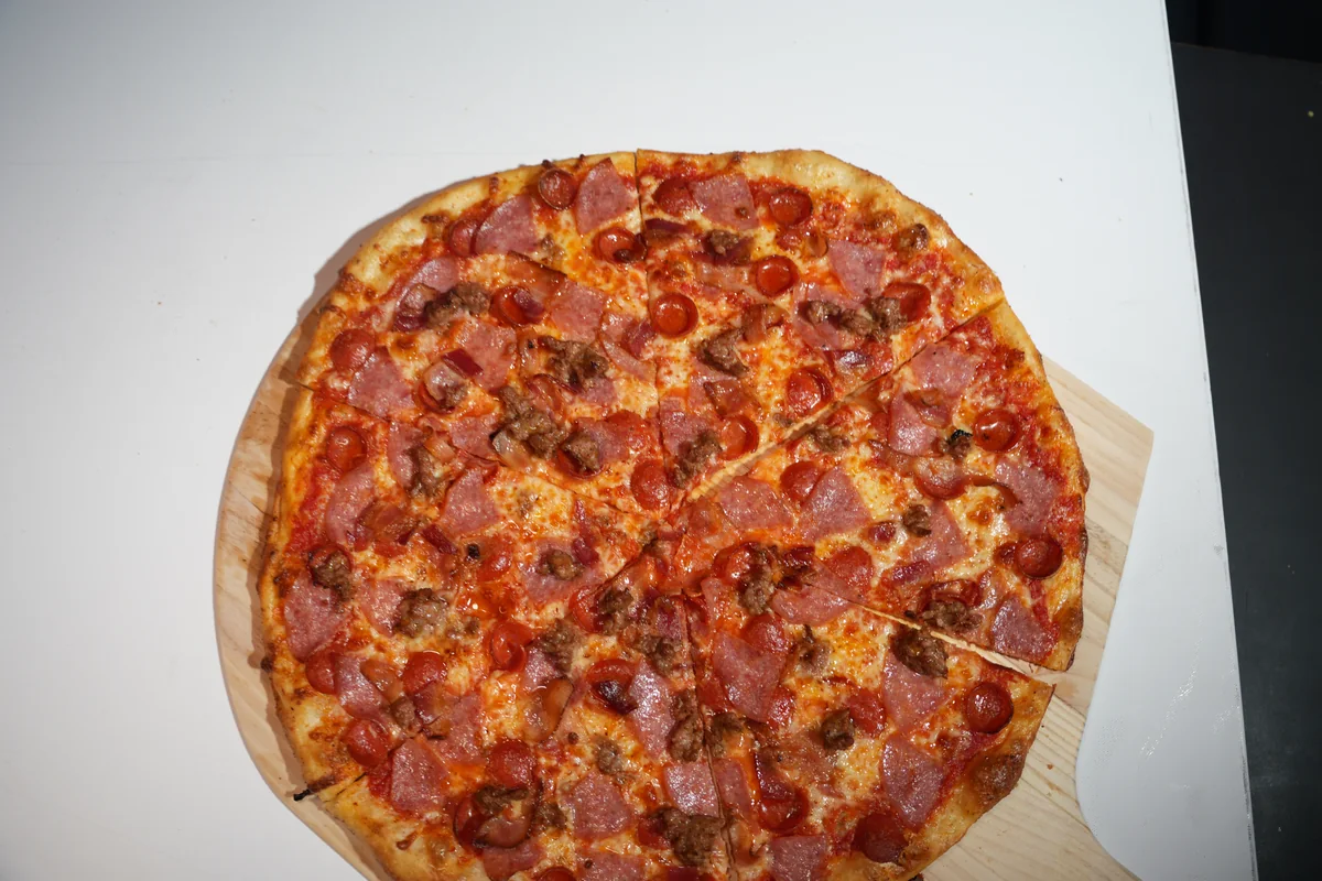 The Priest meat lovers pizza on a wooden pizza board